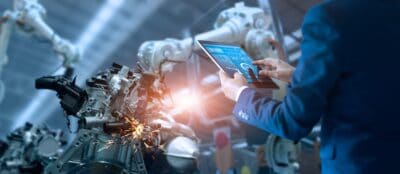 A man in a suit is using a tablet in a factory