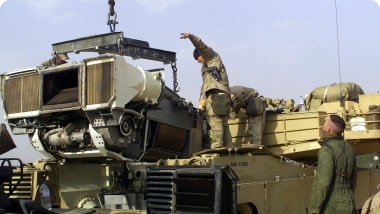 A group of men are working on a military vehicle.