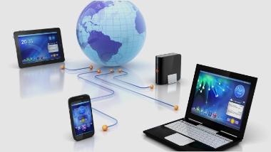A group of laptops, cell phones, and a globe connected to each other.