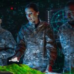 Three uniformed individuals analyze a 3D topographic map in a high-tech room with digital displays and data visuals.