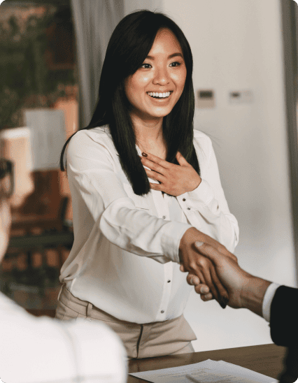 A woman shaking hands with a man in a business meeting.