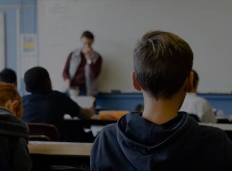 A group of students in a classroom looking at a whiteboard.